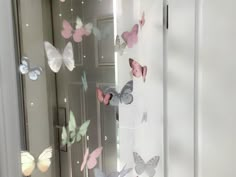 the butterflies are hanging on the wall behind the glass door and in front of the mirror