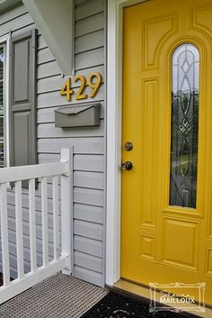 a yellow front door with the number 429 on it and a black mat in front