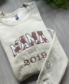 Item Overview * Handmade item * Ships worldwide from Florida Item Details: Mama Embroidered Applique Sweatshirt with shimmer, Customized Gift for Mom , Personalized Mama Shirt, New Mom Gift, Birthday Sweatshirt with Kid's Name Colors displayed: Crewneck color: Sand Thread color: Brown and White Embroidery color choices: White, silver, Prussian blue, cream brown, light blue, sky blue, fresh green, vermillion dark brown, cornflower blue, salmon pink, pink, deep rose,  dark fuchsia, flesh pink, yel Cream Cotton Tops With Letter Embroidery, Cream Cotton Top With Letter Embroidery, White Custom Embroidered Tops For Birthday, Fall Tops With Embroidered Logo As Gift, Customizable White Top With Custom Embroidery, Fall Tops With Embroidered Graphics For Gift, Embroidered Tops For Fall Gift Giving, Embroidered Tops For Fall Gifts, Long Sleeve Tops With Letter Embroidery For Birthday