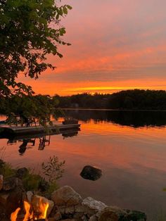 a fire pit sitting next to a lake at sunset