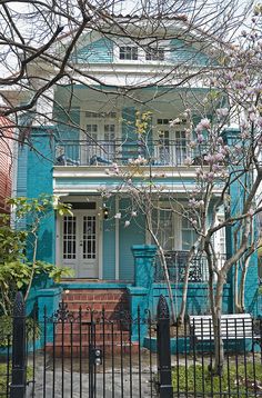 a blue house with black iron fence and trees