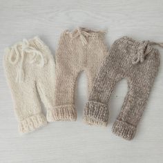 three knitted baby leggings on a white background, one in beige and the other in cream