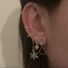 a close up of a person's ear with two star and heart earrings on it