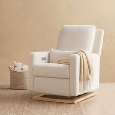 a white rocking chair sitting on top of a hard wood floor next to a pillow