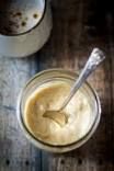 a spoon in a jar filled with food on top of a wooden table next to a cup