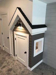 a dog house built into the side of a wall in a room with carpeted flooring