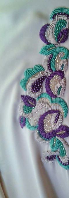 a close up of a white dress with purple and green flowers on it's side