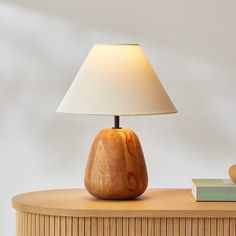 a wooden table with a lamp on top of it and a book next to it