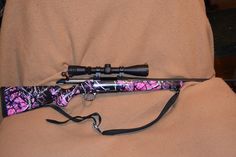 a pink and black camo hunting rod on a tan couch with a brown cover