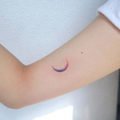 a small crescent tattoo on the arm