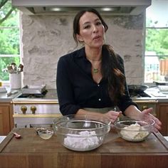 a woman standing in front of a wooden counter with bowls on it and an oven behind her