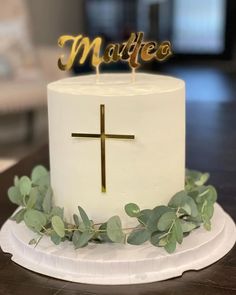 a white cake topped with a cross and greenery