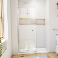 a bathroom with a glass shower door and wooden flooring next to a white toilet