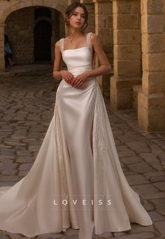 a woman in a white wedding dress standing on a stone walkway with her hand on her hip