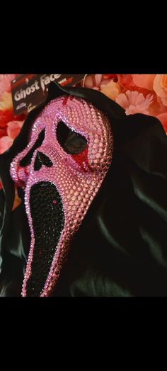 a pink mask on top of a black jacket with flowers in the backgroud