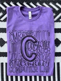 a purple t - shirt with the words computer lab on it sitting on a black and white striped surface