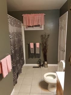 a bathroom with gray walls and pink curtains