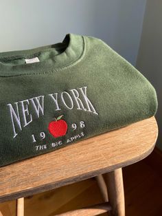 Handmade embroidered New York design onto unisex sweatshirt ✯PRODUCT DETAILS✯ Please note: The photos taken are only indicative every single top is completely handmade therefore all unique! ✯ECO SWEATSHIRT✯  Currently only available in Size Small, Medium and Large  The eco sustainable sweatshirt is made to a very high quality, it's crafted from premium organic and recycled fabrics.  It's 350gsm (so nice and thick) and the inside is a super soft brushed fabric, so will keep you nice and warm! Mat Cheap Embroidered Sweater For Streetwear, Green New York Hoodie, Luxury Urban Sweatshirt With Embroidered Logo, Machine Embroidered Cotton Sweatshirt For Streetwear, Cotton Sweatshirt With Machine Embroidery For Streetwear, Green College Sweatshirt With Embroidered Logo, Fall College Embroidered T-shirt, Long Sleeve Sweatshirt With Machine Embroidery For Streetwear, Long Sleeve Embroidered Sweatshirt For Streetwear