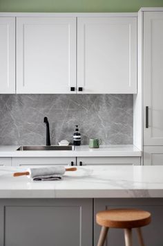 a kitchen with white cabinets and marble counter tops