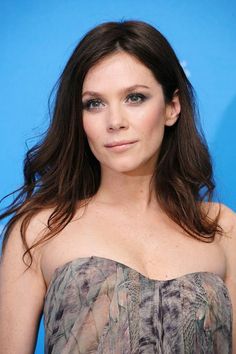 a woman in a strapless dress posing for the camera with long hair and blue eyeshadow