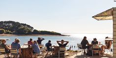 people are sitting at tables near the water