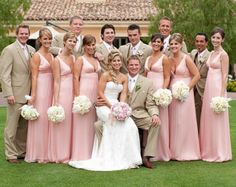 a bride and groom with their bridal party in front of a mansion on the golf course