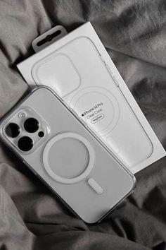 an iphone case sitting on top of a bed next to a box with two buttons