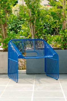 two blue planters sitting next to each other on top of a tiled floor in front of trees