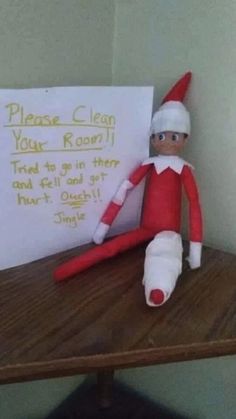 an elf is sitting next to a sign that says please clean your room trust us in their and call me out