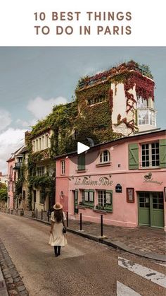 a woman walking down the street in front of pink buildings with ivy growing on them