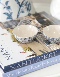 two blue and white bowls sitting on top of a table next to a book about nantucket