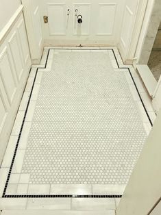 a bathroom with white walls and tile flooring next to an open door that leads to another room