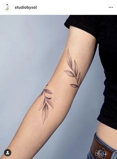 a woman's arm with a tattoo on it that has leaves growing out of it