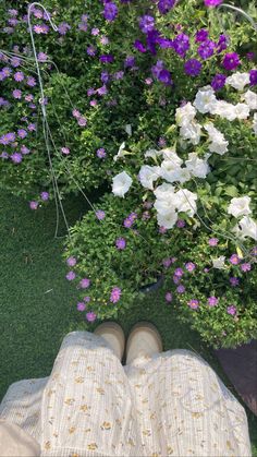 the person is laying down in front of some purple and white flowers with their feet up