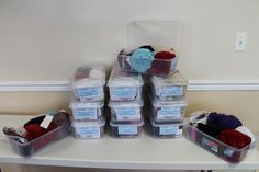 several plastic containers filled with yarn on top of a white table next to a wall