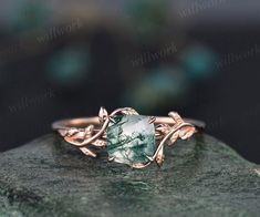 a green ring with leaves on it sitting on top of a rock in front of a black background