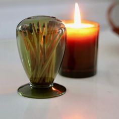 a lit candle sitting on top of a table next to a vase filled with flowers