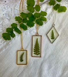 two pendants with green leaves on them are hanging from a branch next to a white lace tablecloth