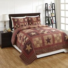 a bed covered in a brown and tan quilt with stars on the comforter next to a night stand