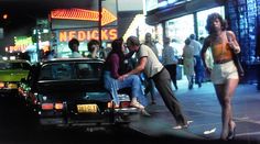 people are standing on the sidewalk in front of a car