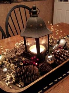 a lantern is sitting on top of a tray with pine cones and other christmas decorations