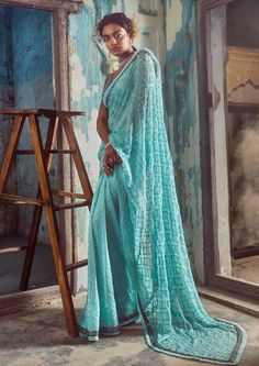 Editor's Note This aqua blue chiffon sari and net blouse set is a beautiful and elegant choice for any formal occasion. The sari is crafted from a lightweight chiffon fabric in a stunning aqua blue color that is perfect for warm weather events. The net blouse is intricately embroidered with self and gunmetal sequins, beads, and crystals, adding a touch of sparkle and glamour to the ensemble. Color: Blue Fabric: Sari: georgette, chiffon blouse: raw silk, lining: shantoon Components: Sari and blou Festive Silk Chiffon Saree Blouse Piece, Blue Anarkali Style Pre-draped Georgette Saree, Festive Blue Georgette Pre-draped Saree, Festive Silk Chiffon Saree, Blue Pre-draped Saree With Chikankari Embroidery, Light Blue Designer Saree Set, Designer Light Blue Saree Set, Elegant Turquoise Set With Dupatta, Festive Turquoise Pre-draped Saree