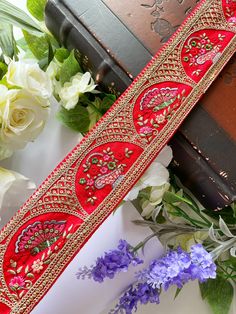 a close up of a red ribbon with flowers in the background