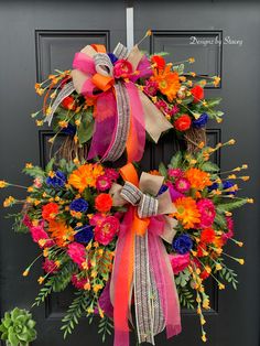 a colorful wreath on the front door of a house that is decorated with flowers and ribbons