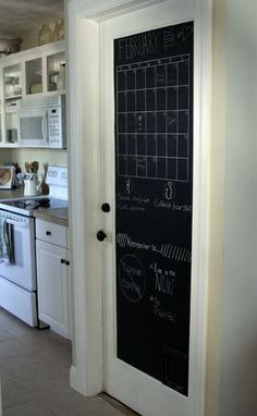 a chalkboard door is open to reveal the kitchen's white cabinets and appliances