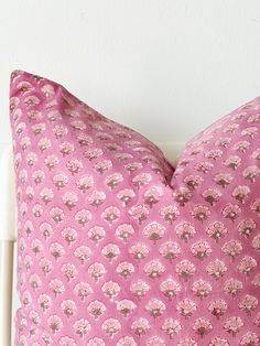 a pink pillow sitting on top of a white chair