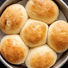 a metal bowl filled with rolls on top of a table