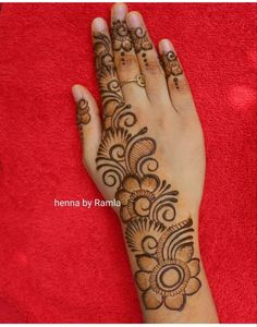 henna by ramma on her hand with flowers and swirls in the middle