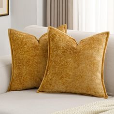 two yellow pillows sitting on top of a white couch