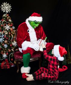 a man dressed as santa claus sitting on a chair next to a small christmas tree